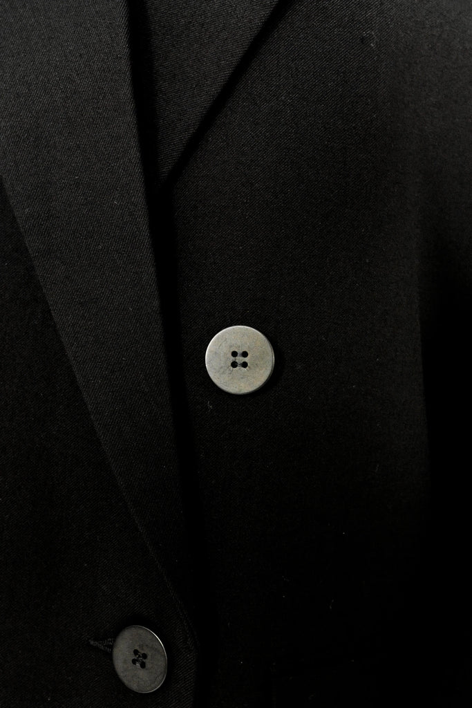 Close-up of a person wearing the ALVA Blazer in Tuxedo Black. Only the buttons are visible.